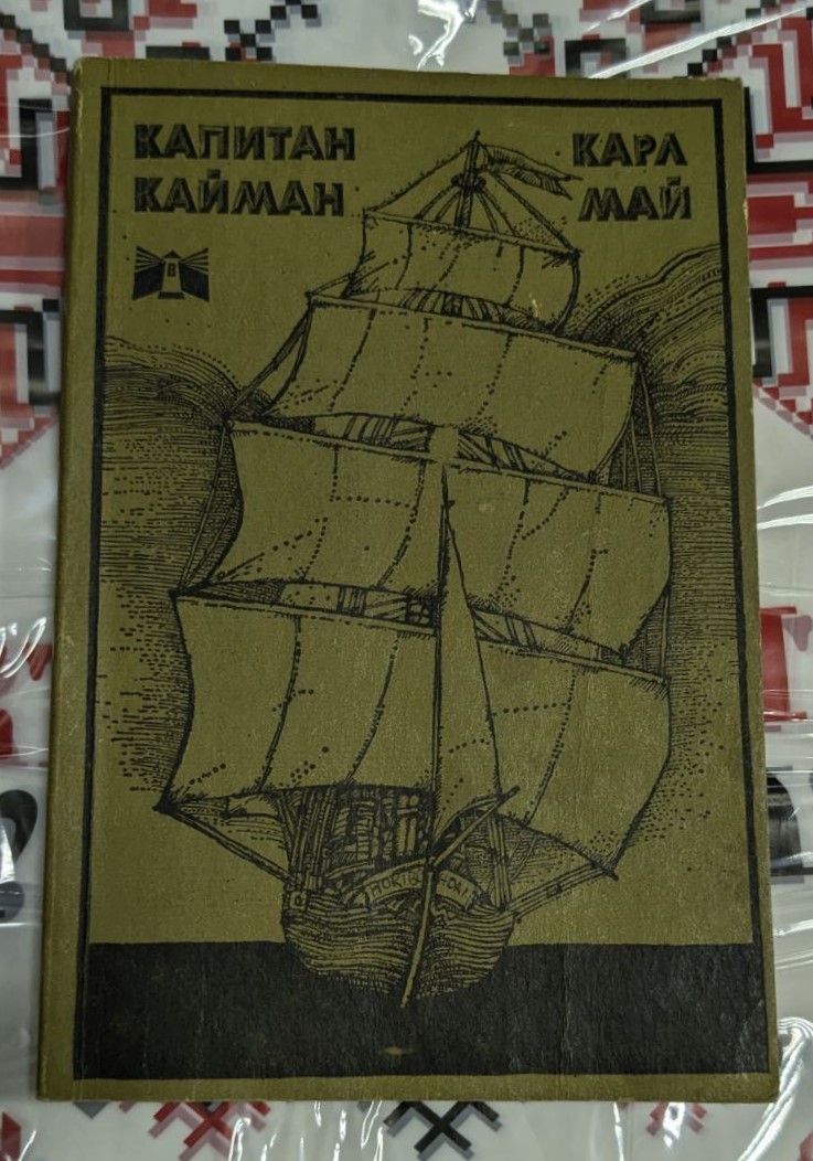 Корицата на „Капитан Кайман“ от Карл Май, издание от 1979 г. с тънки корици, показва приключенската и екзотична атмосфера на романа, вдъхновен от тропическите джунгли.