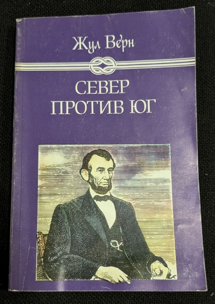 "Север против Юг" от Жул Верн, първо издание от 1986 година, роман, представящ приключенски и научно-фантастични теми с характерния стил на Верн.