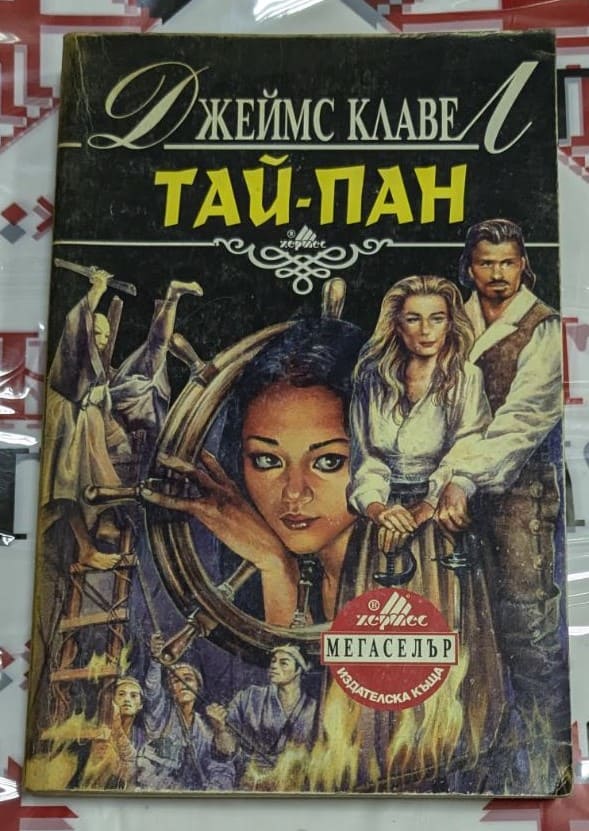 Корица на романа „Тай-Пан“ от Джеймс Клавел, изобразяваща динамична сцена от колониална Азия с исторически елементи и силни герои.