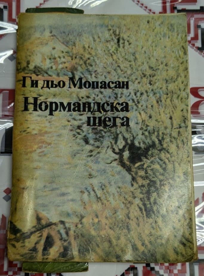 Корицата на „Нормандска шега“ от Ги Дьо Мопасан (1985) представя класически и елегантен дизайн, отразяващ темите на избраните разкази.