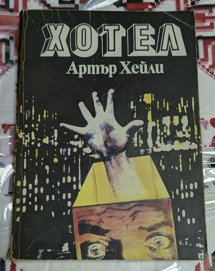 Корицата на романа "Хотел" от Артър Хейли, издаден през 1990 г., с луксозен фон и елегантни елементи, символизиращи света на хотелиерството.