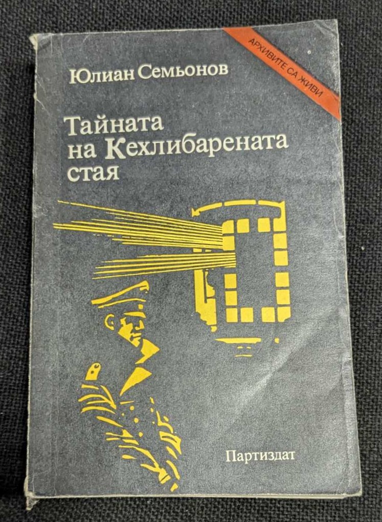 Корицата на романа „Тайната на Кехлибарената стая“ от Юлиан Семьонов, издание от 1985 г., с изобразен съветски разузнавач и влакова композиция на тъмен фон.
