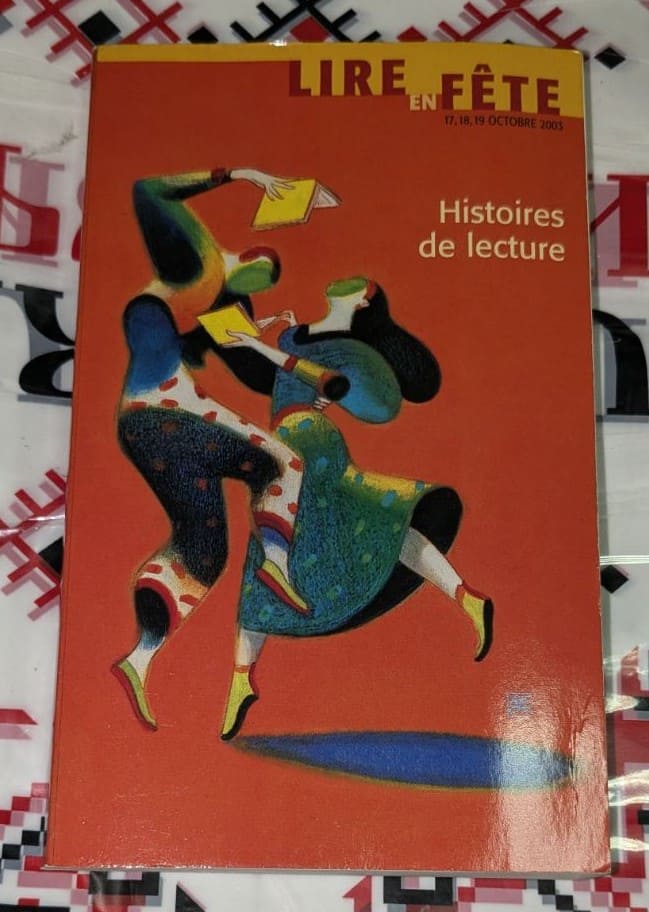 Корица на издание за фестивала „Lire en Fête“ 2003 с абстрактна илюстрация на танцуващи фигури, държащи книги, върху червен фон.