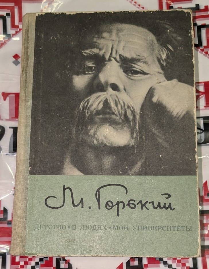 Книга на Максим Горки с черно-бяла корица, включваща негов портрет и заглавията на автобиографичната му трилогия.