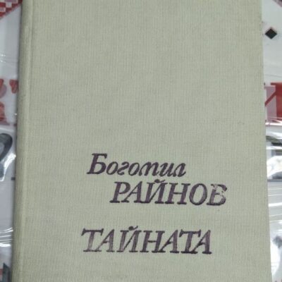 Корица на книгата Тайната от Богомил Райнов, изчистен дизайн с текст в лилав шрифт върху светъл платнен фон.
