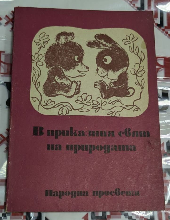 Корица на детската книга „В приказния свят на природата“ с илюстрация на мече и зайче, седящи едно срещу друго, на бордо фон.