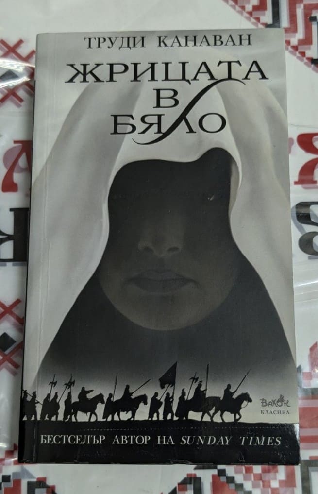 Корица на книгата 'Жрицата в бяло' от Труди Канаван с мистичен дизайн и символика. Лого на ВАКОН ООД