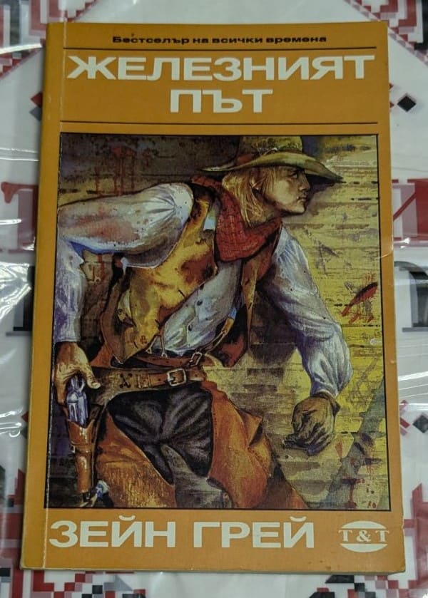 Корица на книгата „Железният път“ от Зейн Грей с илюстрация на каубой, облечен в жилетка и шапка, който държи револвер.
