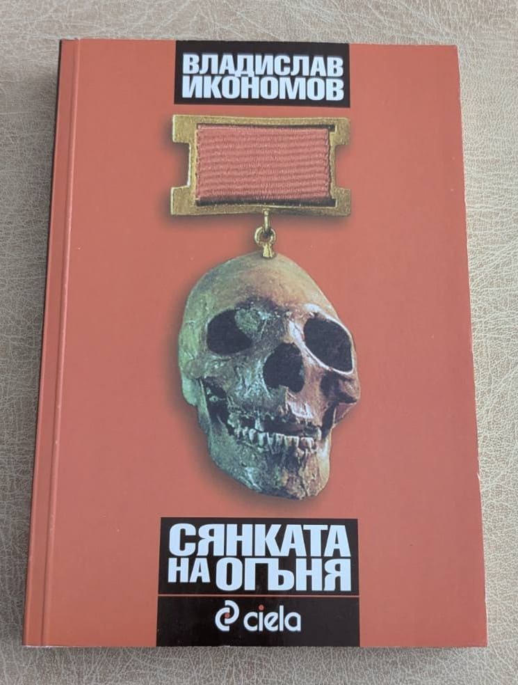 Книга „Сянката на огъня“ от Владислав Икономов, издание Ciela, с череп и медал на корицата.